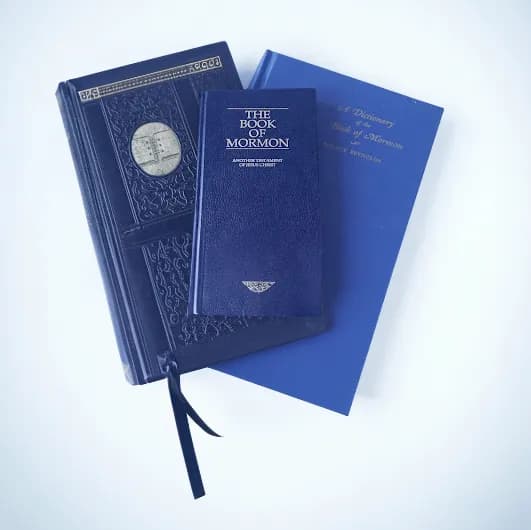 Books of Mormon stacked on a wooden surface, illustrating LDS scriptures